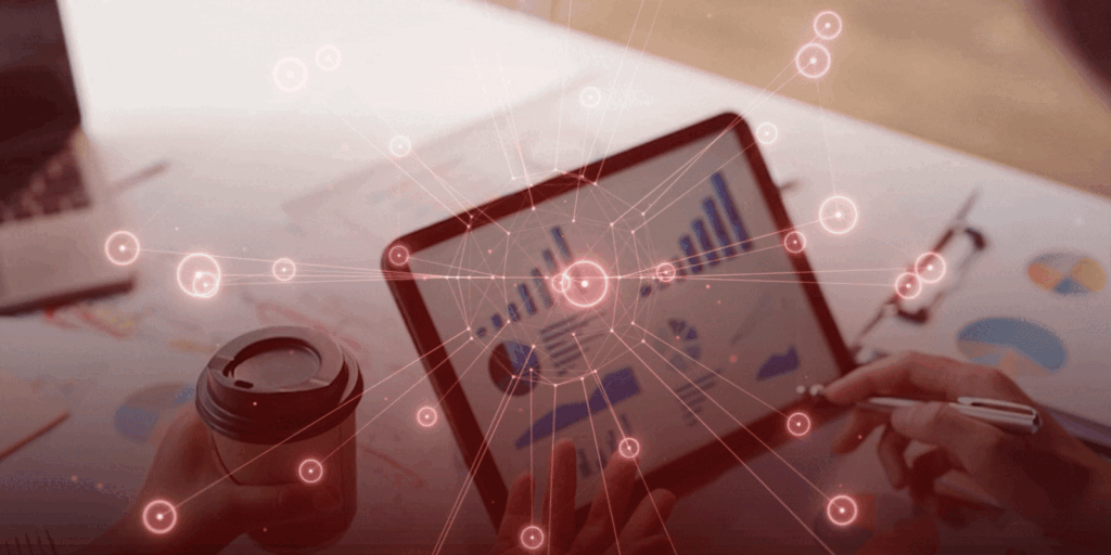 Tablet displaying graphs on a desk filled with documents. Two hands, one holding coffee, other a stylus, with digital network overlay suggesting analysis.